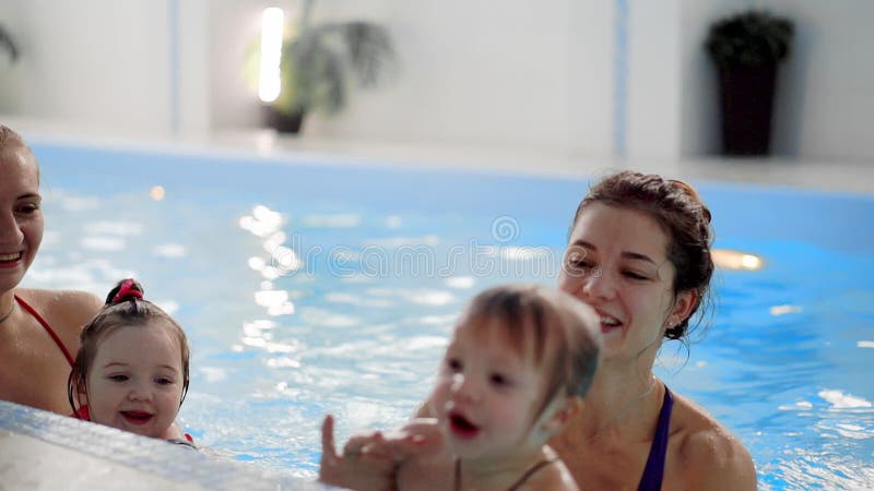 Groep mums met hun babykinderen bij zuigelings zwemmende klasse