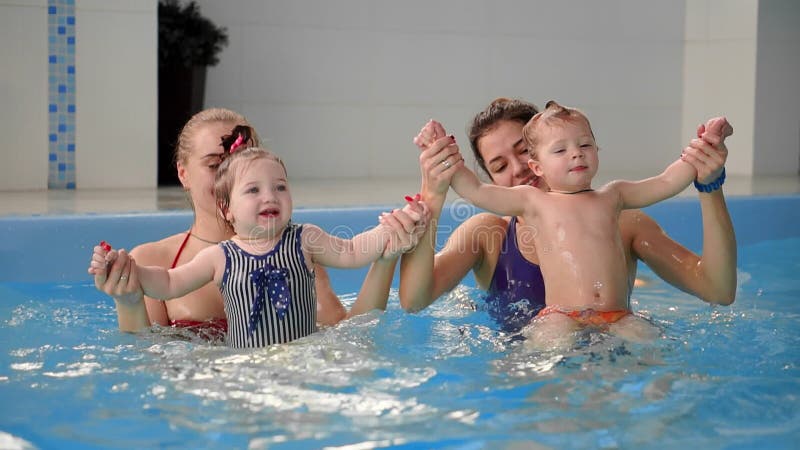 Groep mums met hun babykinderen bij zuigelings zwemmende klasse