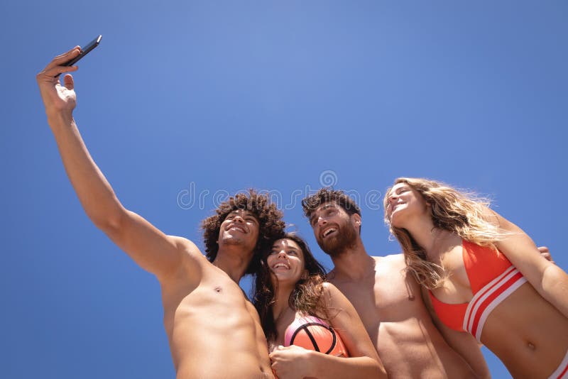Groep vrienden die selfie met mobiele telefoon bij strand in de zonneschijn nemen royalty-vrije stock foto's Groep vrienden die selfie met mobiele telefoon bij strand in de zonneschijn nemen royalty-vrije stock foto's