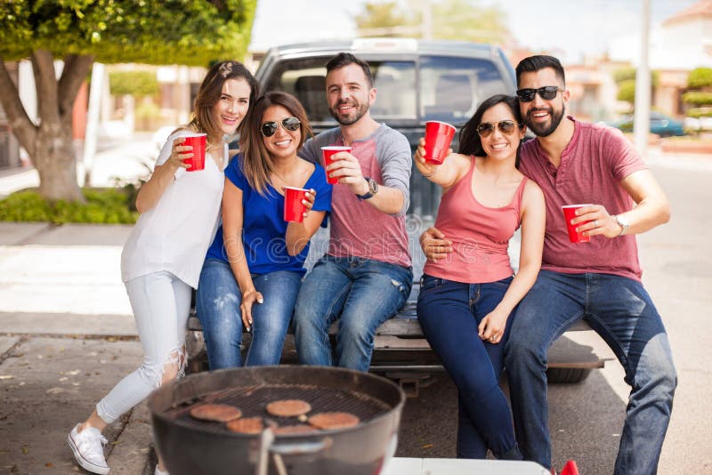 Groep vrienden tailgating en het roosteren van burgers royalty-vrije stock fotografie Groep vrienden tailgating en het roosteren van burgers royalty-vrije stock fotografie