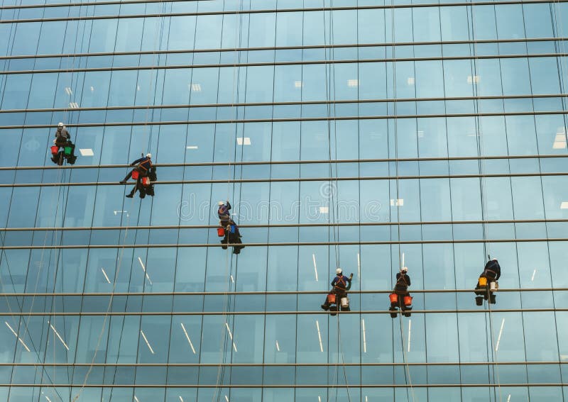 Groep werknemers die de dienst bij de generaal/hoge stijgingsbouw schoonmaken. De industriële klimmers van vensterwasmachines
