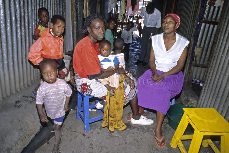 Kenya, capital, city Nairobi, neighborhood Lunga Lunga: everyday living in the slum Mutunga, a wife, mother sits with her child, daughter, baby on lap, while her children and that of the female neighbor are playing in the narrow, dark, corridor between the corrugated iron houses. Housing and living conditions are very primitive and shabby. Kenya, capital, city Nairobi, neighborhood Lunga Lunga: everyday living in the slum Mutunga, a wife, mother sits with her child, daughter, baby on lap, while her children and that of the female neighbor are playing in the narrow, dark, corridor between the corrugated iron houses. Housing and living conditions are very primitive and shabby.