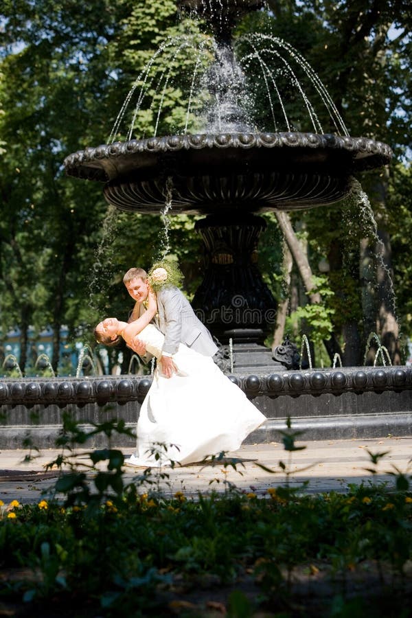 Groom and bride joy against backdrop fountain