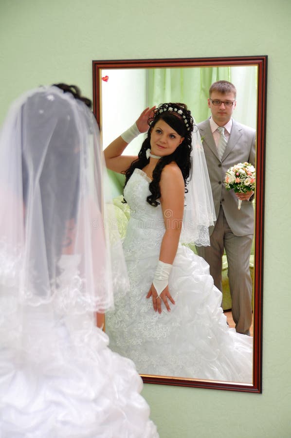 The groom and the bride look in a mirror