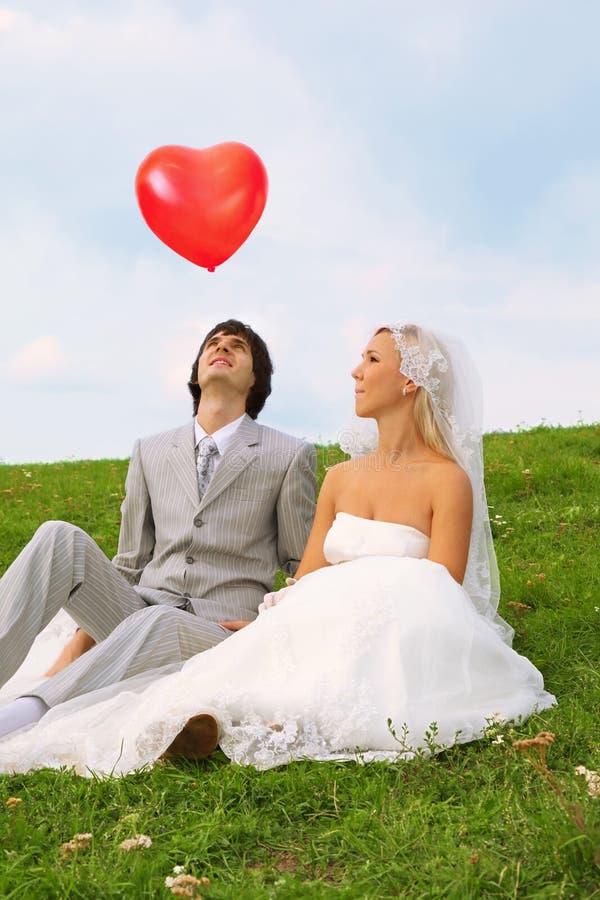 Groom and bride looking at red balloon stock photos Groom and bride looking at red balloon stock photos