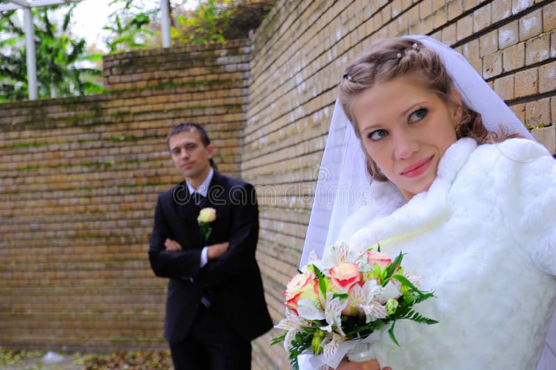 The groom and the bride near a wall