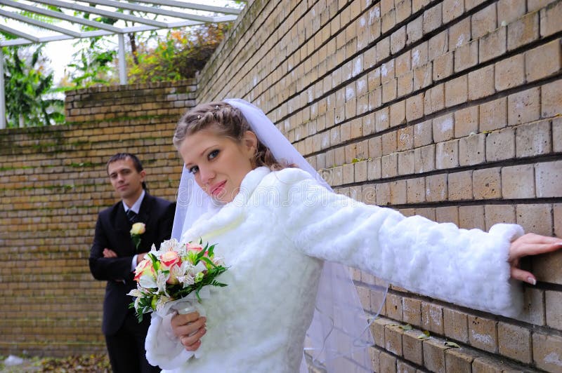 The groom and the bride near a wall