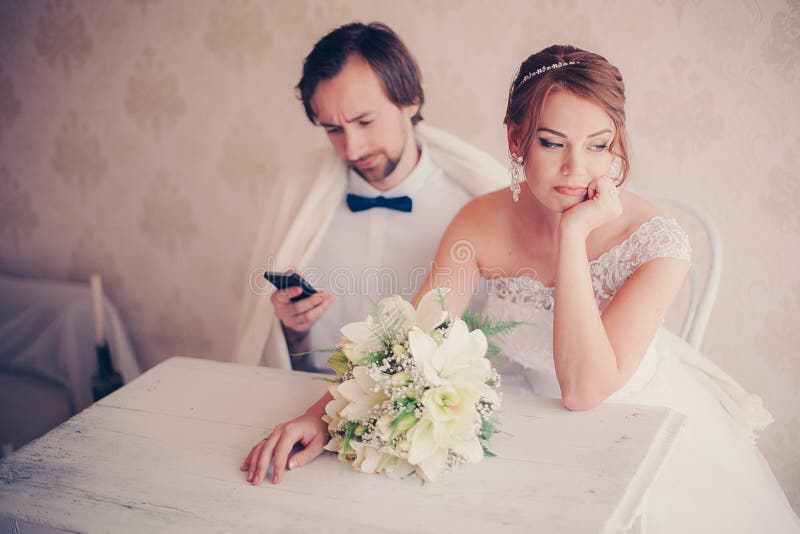 Groom is distracted with the phone at wedding photosession