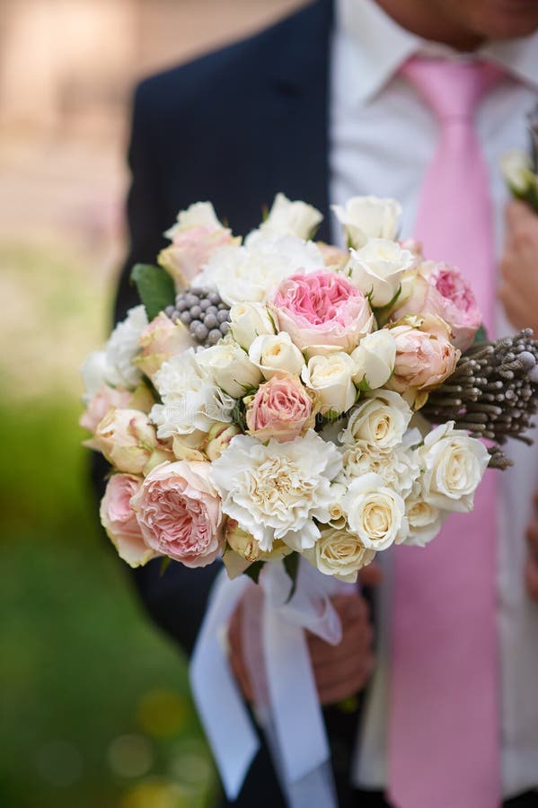 Groom holds the beautiful bride bouquet in wedding morning