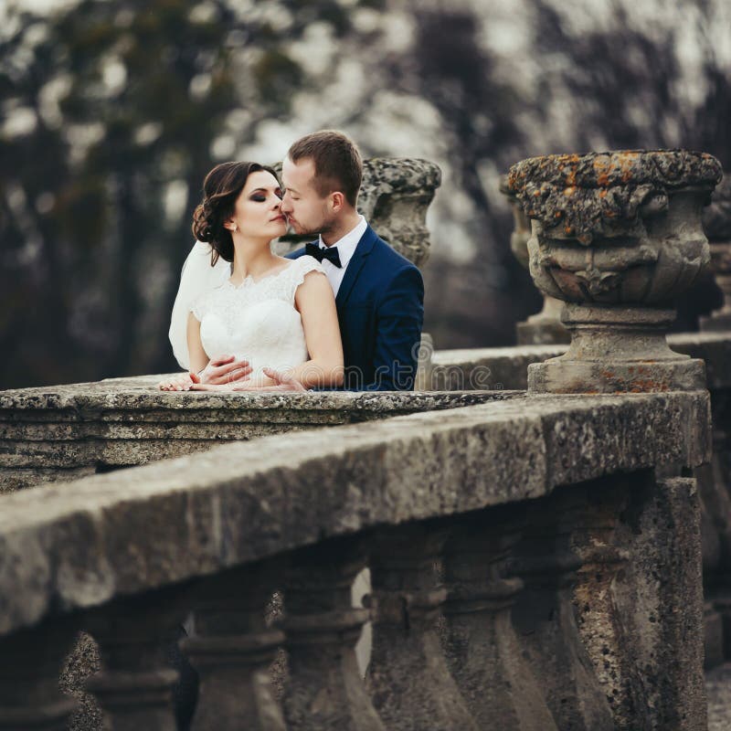 Groom kisses a bride hugging her from behind on the old balcony royalty free stock photography