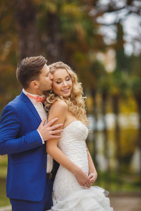 The groom kisses the bride in Park in the summer.