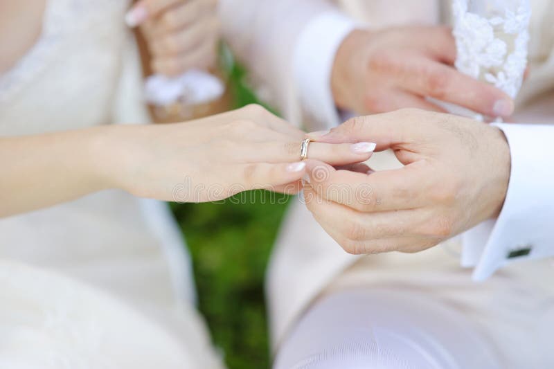 Groom putting a ring on bride's finger royalty free stock images