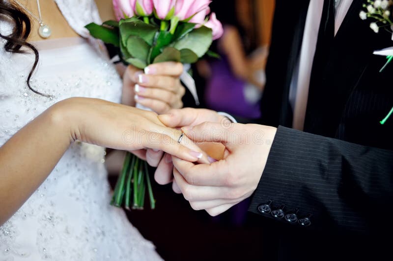 Groom putting on wedding ceremony for bride gold ring on the finger