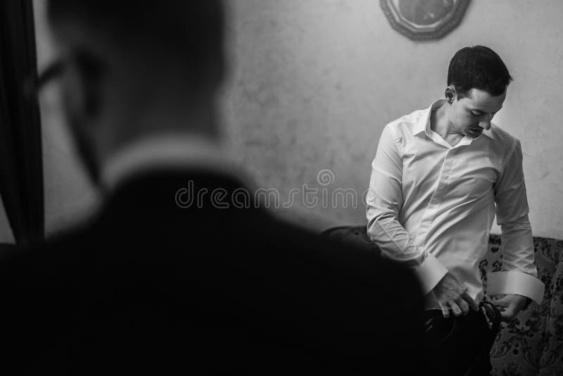 Groom staat 's morgens klaar met groomsmen in de kamer manuele handen die jasje en boegdas aantrekken, staan aan het raam royalty-vrije stock fotografie Groom staat 's morgens klaar met groomsmen in de kamer manuele handen die jasje en boegdas aantrekken, staan aan het raam royalty-vrije stock fotografie