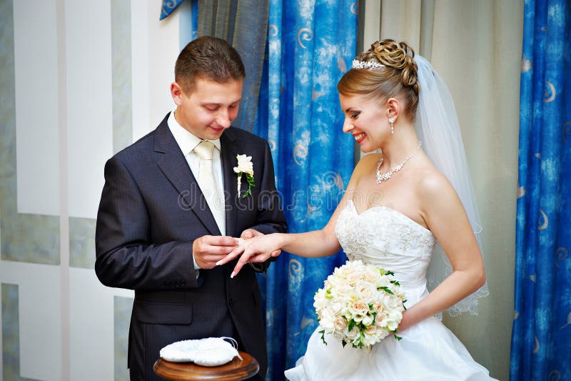 Groom wears wedding ring happy bride