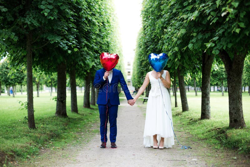 Groom и невеста с воздушными шарами на тротуаре стоковое изображение rf Groom и невеста с воздушными шарами на тротуаре стоковое изображение rf