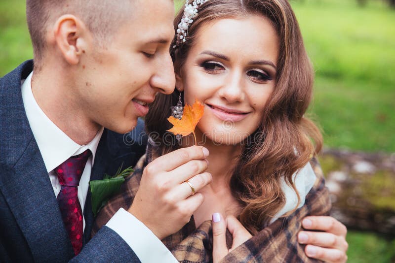 Groom обнимая его невесту в парке ювелирные изделия cravat пар кристаллические связывают венчание стоковые изображения rf Groom обнимая его невесту в парке ювелирные изделия cravat пар кристаллические связывают венчание стоковые изображения rf