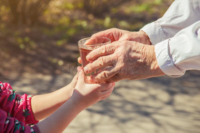 Grootmoeder die een glas schoon water geven aan een kind stock afbeelding Grootmoeder die een glas schoon water geven aan een kind stock afbeelding