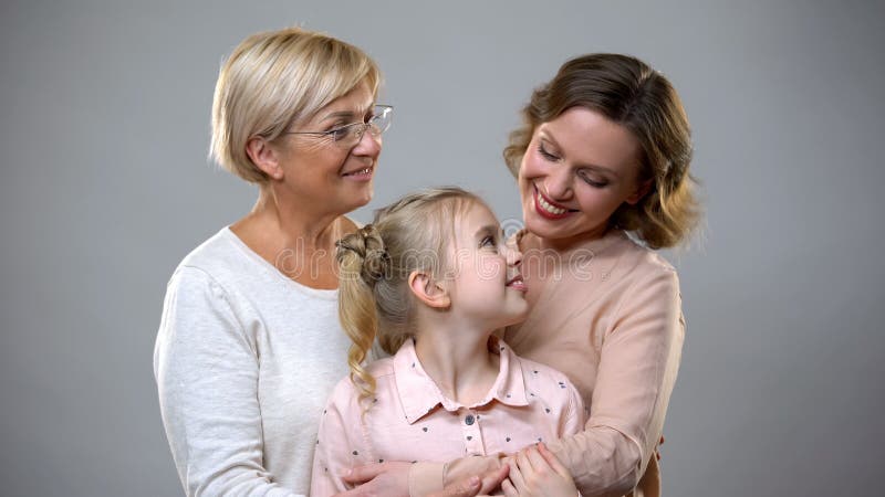 Grootmoeder, dochter en kleinkind die op grijze achtergrond, vertrouwensrelaties koesteren stock foto Grootmoeder, dochter en kleinkind die op grijze achtergrond, vertrouwensrelaties koesteren stock foto