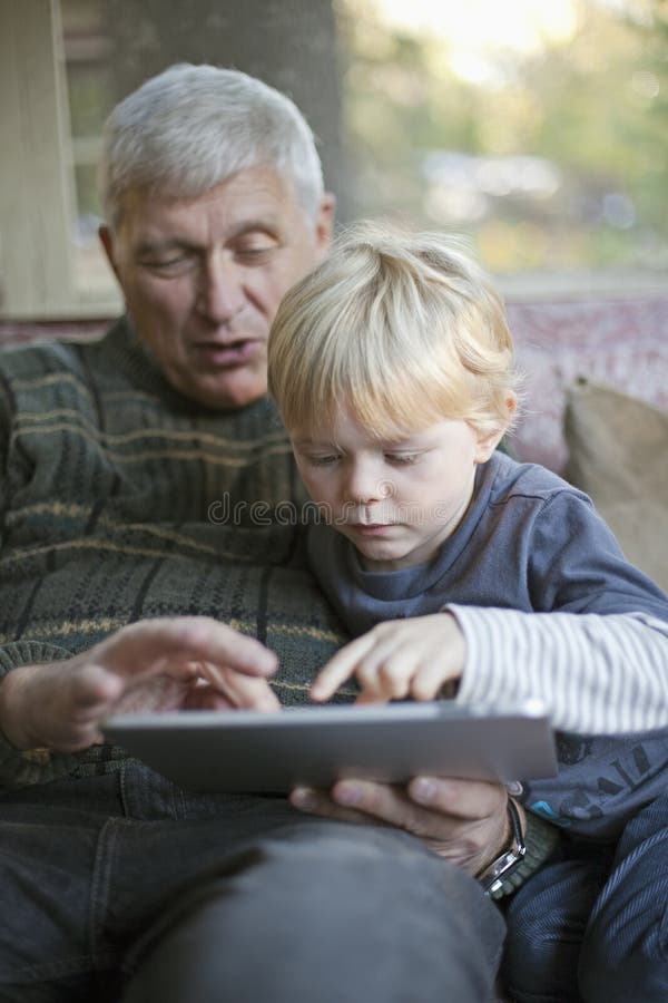 Grootvader en kleinzoon die PC van de Tablet met behulp van