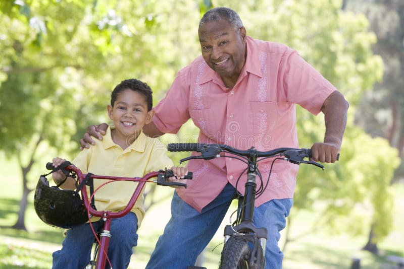 Grootvader en kleinzoon op fietsen die in openlucht glimlachen