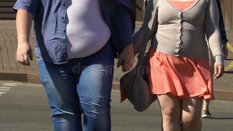 Gros couples dans la rue de croisement d'amour tenant les mains, problème d'obésité dans la société