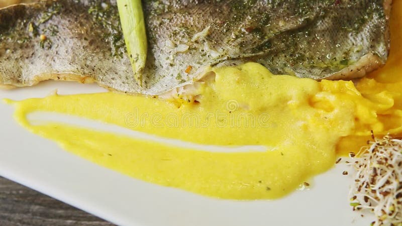 Gros filet de poisson rôti sur purée de pommes de terre et légumes tranchés tourne sur l'assiette clips vidéos