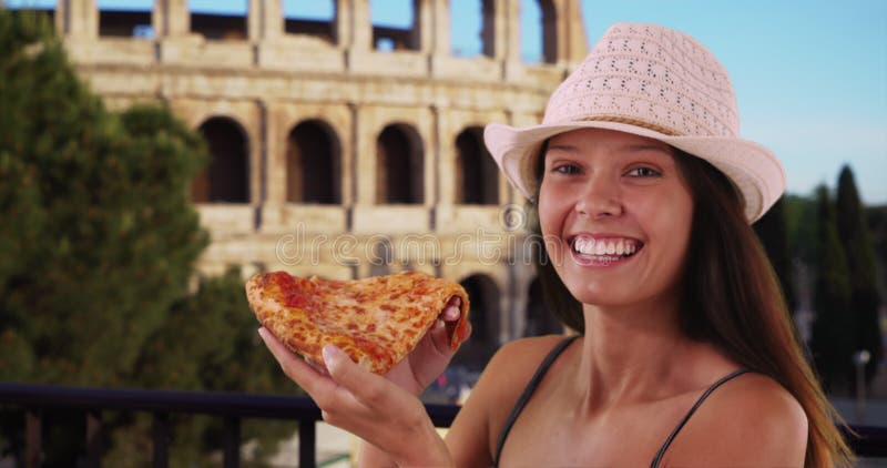 Gros plan d'une jeune femme touristique près du colisée romain manger pizza banque de vidéos