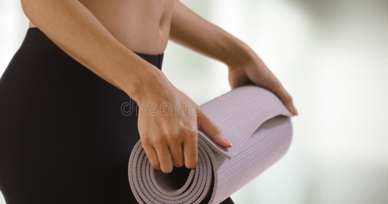 Gros plan de femme en train de monter le tapis de yoga.