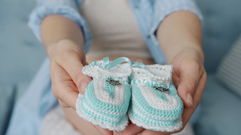 Gros plan de femme enceinte étendant la main qui tient les bottes tricotées mignons bébé clips vidéos