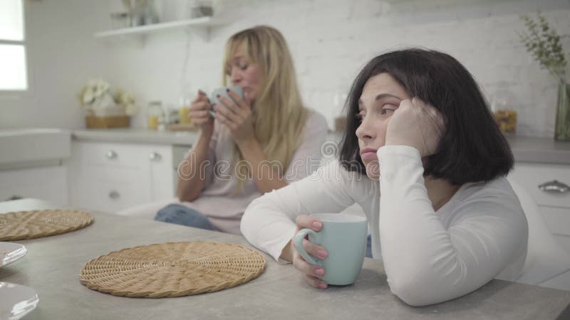 Gros plan de la femme du caucase brune adulte retrouvent aussi bien avec une tasse de café à la table Boire son amie blonde femel