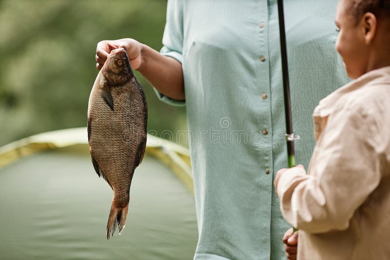 Gros plan de la main femelle tenant du poisson à l'extérieur pendant la sortie de pêche en famille images libres de droits