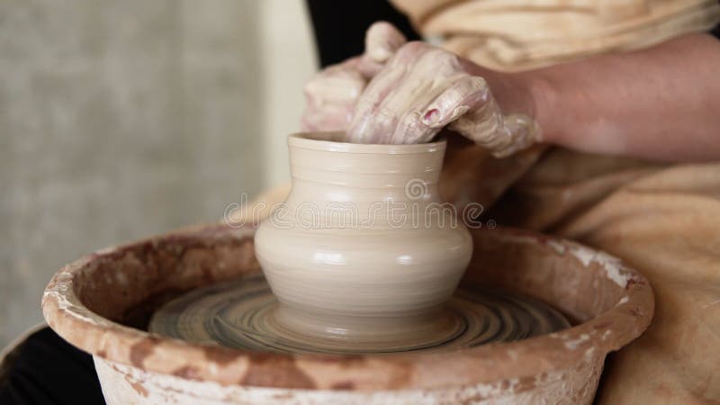 Gros plan des mains de potiers fonctionnant avec de l'argile humide sur une roue de poterie faisant un vase dans un atelier. Mécon banque de vidéos