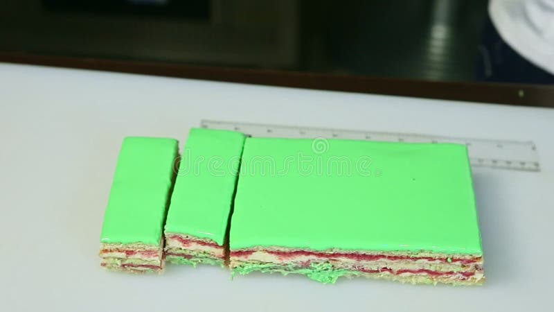 Gros plan en tranches sur le gâteau posé vitré vert de parties avec le remplissage crémeux de fruits banque de vidéos