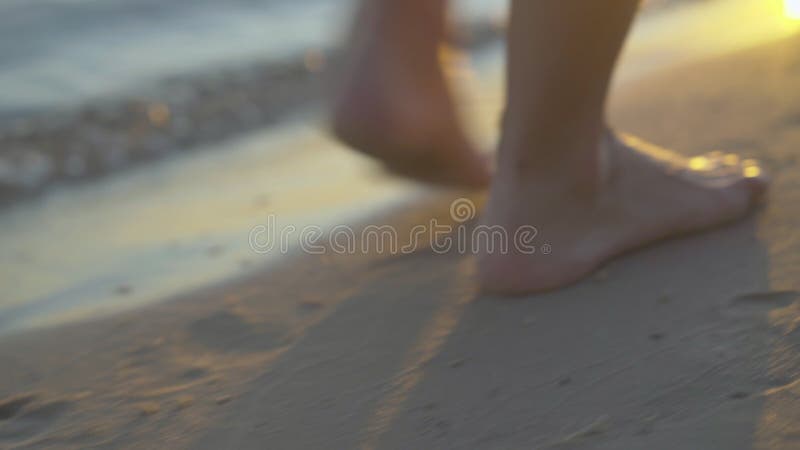 Gros plan extrême de jeunes femmes caucasiens pieds en marchant le long de la plage de sable au coucher du soleil. Femme aux pieds