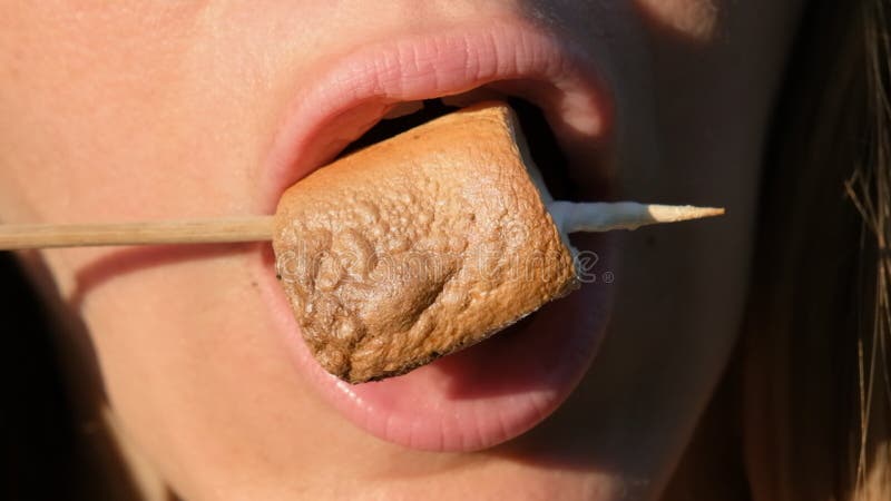 Gros plan sur une fille mangeant un marshmallow cuit sur un bâton 4k résolution vidéo au ralenti de cuisson ou torréfié clips vidéos