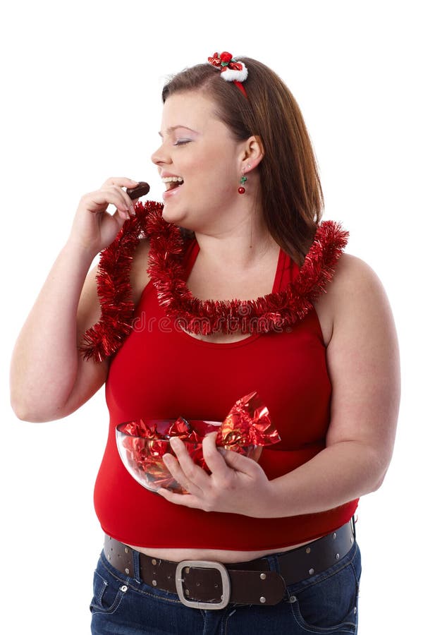 Grosse femme mangeant du chocolat au sourire de Noël image libre de droits Grosse femme mangeant du chocolat au sourire de Noël image libre de droits