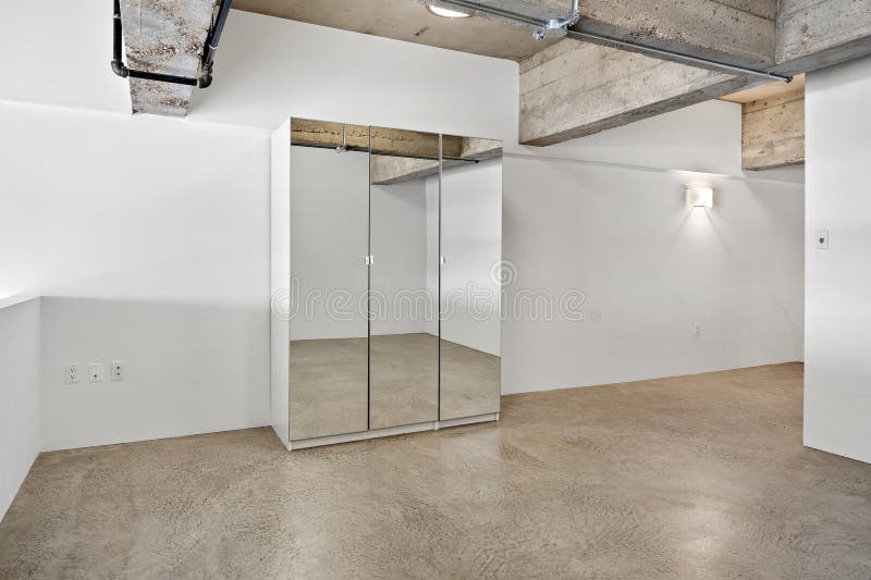 Großer Raum mit einer weißen Wand und einer weißen Kommode mit Spiegel stockfoto