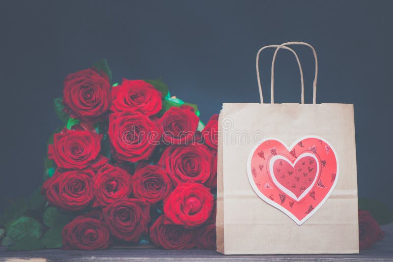 Grote bos van rode rozen en een giftzak met een hart Het concept een gift voor de Dag van Valentine, liefde, huwelijk stock foto Grote bos van rode rozen en een giftzak met een hart Het concept een gift voor de Dag van Valentine, liefde, huwelijk stock foto