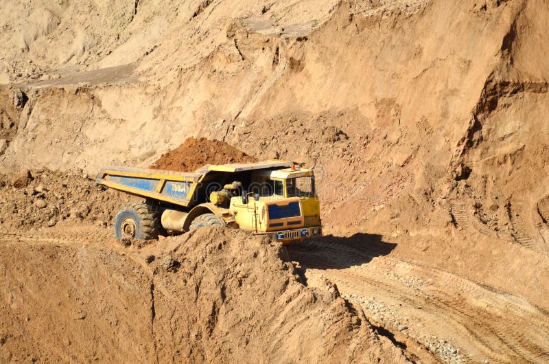 Grote gele vuilniswagen die zand vervoert in een open steengroeve Mijngroeve voor de productie van steenslag, zand en