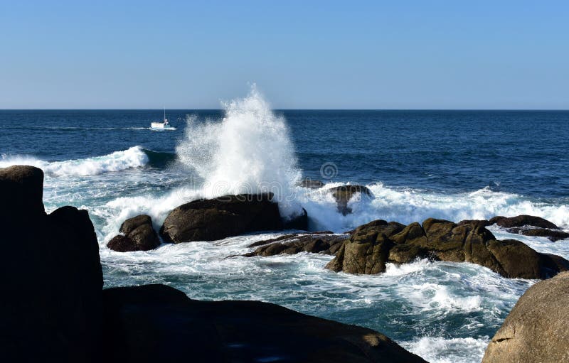 Grote golven die tegen de rotsen en de vissersboot bespatten Blauwe overzees met wit schuim, zonnige dag Galicië, Spanje royalty-vrije stock foto's Grote golven die tegen de rotsen en de vissersboot bespatten Blauwe overzees met wit schuim, zonnige dag Galicië, Spanje royalty-vrije stock foto's