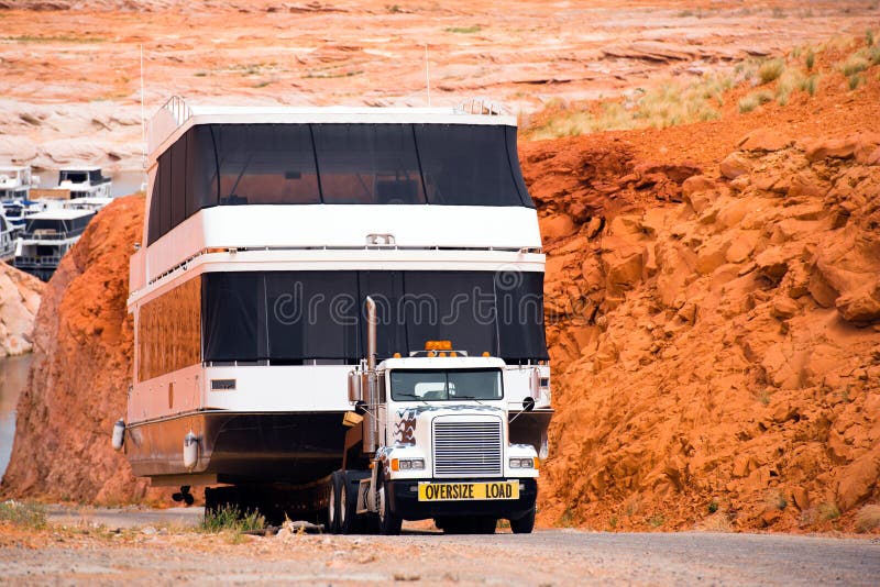 Big powerful American rig semi truck fleet go down the red rocks hill to the water a huge oversize ship on marine resort at Lake Paul in Page Arizona. Big powerful American rig semi truck fleet go down the red rocks hill to the water a huge oversize ship on marine resort at Lake Paul in Page Arizona.