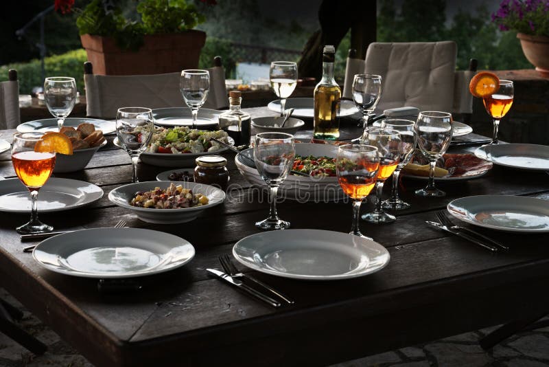 Large rustic table prepared with mediterranean salads and antipasti for a garden dinner at night, selected focus. Large rustic table prepared with mediterranean salads and antipasti for a garden dinner at night, selected focus