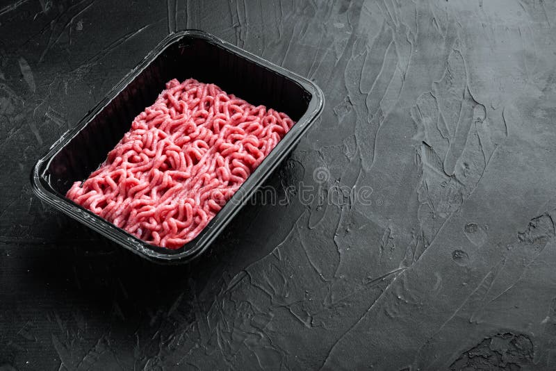Ground Beef Meat in Plastic Tray, on Black Stone Background, with Copy