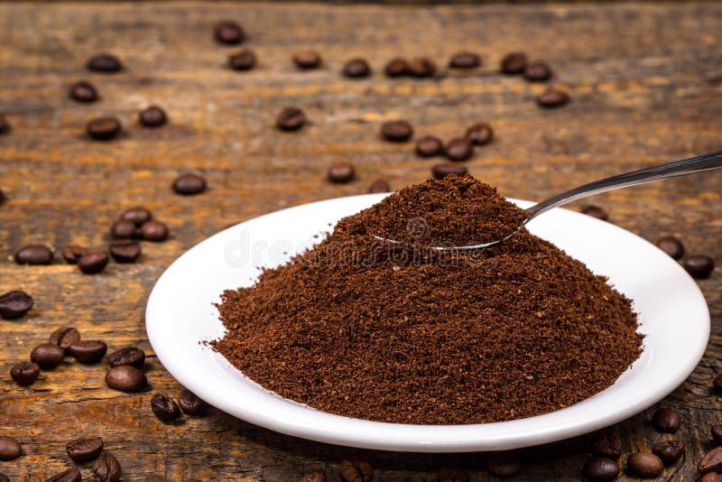 Ground Coffee on White Plate with Sorrounding Coffee Beans Stock Image