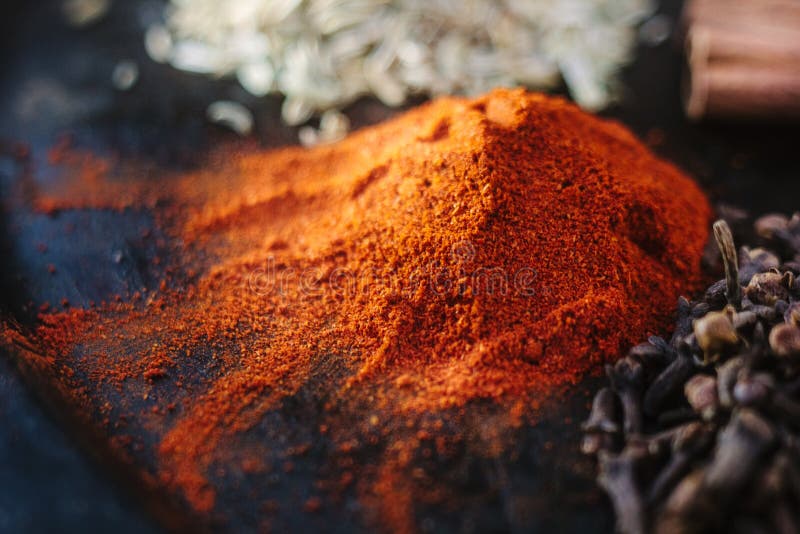 Grounded Chili Pepper on Black Rustic Surface, Surrounded by Spices