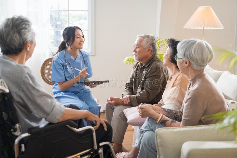 Group of Asian senior people sit in a circle in a nursing home and listen to nurse during a group elderly therapy session.