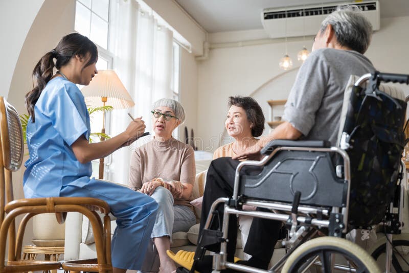 Group of Asian senior people sit in a circle in a nursing home and listen to nurse during a group elderly therapy session.