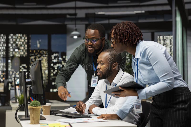 Group of black employees doing teamwork on important task late at night, collaborating on building a new development strategy after hours. Reviewing insights to enhance efficiency. Reading efficiency stock images, royalty-free photos and pictures
