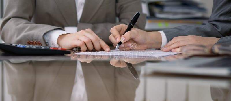 Group of business people and lawyers discussing contract while sitting at the table. Woman chief is taking pen for stock photography